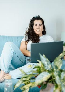 Emprendedora creativa frente a su portátil, mirando al frente y sonriendo.